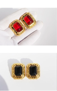 Macro detail of vintage baroque style earrings with red and black gems in gold frames
