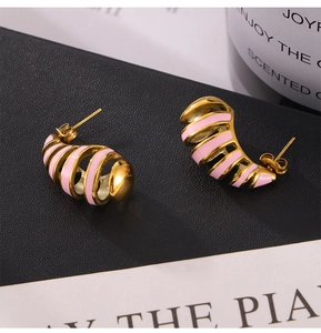 Macro shot of striped C-shaped stud earrings in gold metal with pink enamel texture