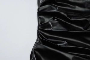 Gros plan sur le simili cuir noir montrant les détails des fronces et des reflets