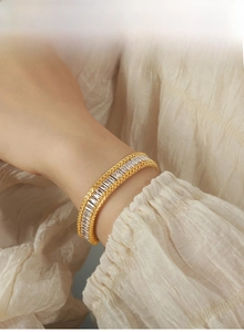 Close-up of elegant gold titanium bracelet with rectangle zircons and braided edges