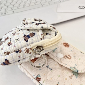 Detailed macro view of quilted fabric card holder with bear patterns and metal ring zipper