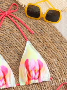 Detailed view of floral print bikini top with halter neck ties on a beach mat