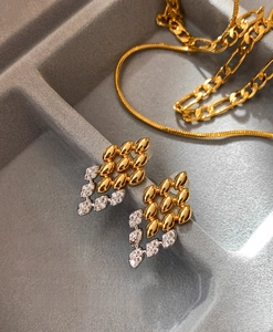 Macro d'oreilles dorées en forme de feuille avec zircons sur un plateau à bijoux