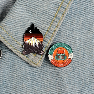 Camping enamel pins set with bonfire and backpack designs on denim jacket collar