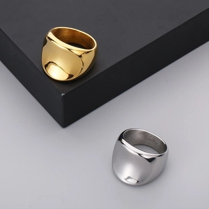 Polished gold and silver stainless steel chunky rings displayed on a sleek black box