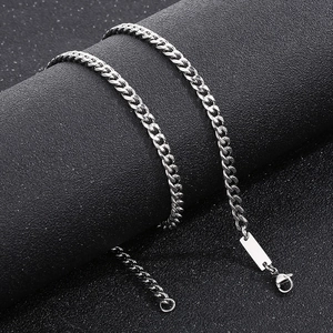 Detail of silver Cuban chain necklace with rectangular plate on black textured surface