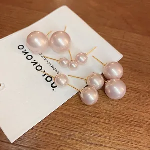 Elegant set of multi-size round pearl stud earrings with gold pins on a white card