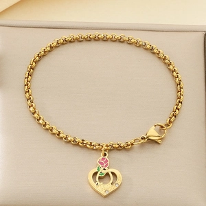 Détail d'un bracelet doré avec pendentif cœur Mom et décoration de petite rose rose