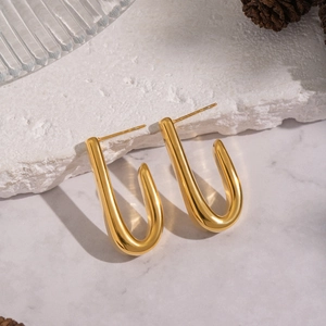 Detail of 18K gold-plated U-shaped earrings on a marble stone with natural textures