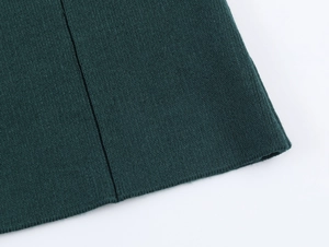 Detailed macro view of dark green knit fabric showing fine stitching and smooth texture