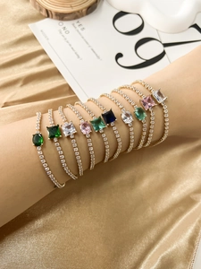 Close-up of colorful gemstone tennis bracelets stacked on wrist with gold plating