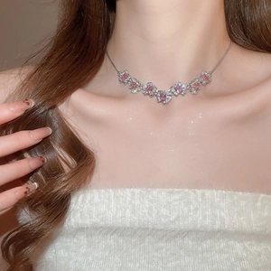 Detail view of a silver flower necklace with pink zircon stones worn on a white sweater
