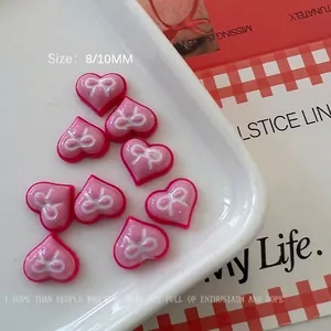 Macro detail of pink resin heart nail charms with white bow design in 8mm and 10mm sizes