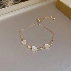 Close-up of golden heart bracelet with white zircon stones on silk tray surface