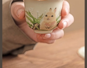Macro view of Ru ware ceramic tea cup with hand-painted rabbit and floral patterns