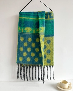 Detail of knit scarf with blue, green, yellow blocks, polka dots, and black tassels