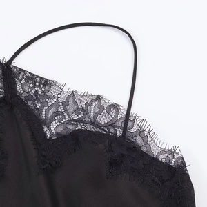 Detailed macro view of black satin fabric with delicate floral lace trim on the neckline