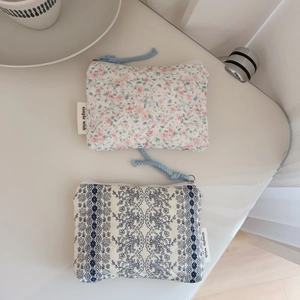 Detailed shot of quilted floral and lace mini fabric pouches with blue woven zipper pulls