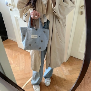 Light blue corduroy tote bag with bear embroidery shown in a stylish lifestyle setting