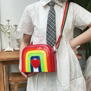 Detail view of rainbow striped crossbody bag featuring a bold red heart patch and strap