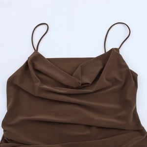 Detail of cowl neck design and thin straps on a glossy brown satin pleated dress