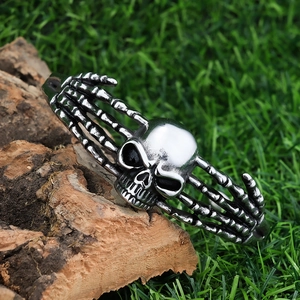 Silver stainless steel punk skull hand bone open bangle on a natural wooden background