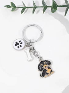 Macro detail of dachshund keychain with bone and paw charms on white display background