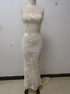 Detailed close-up of 3D floral embroidery and mesh fabric on a white fishtail evening dress
