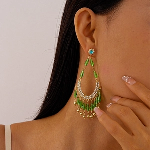 Close-up of green crystal teardrop tassel earrings with blue rhinestone detail