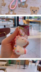 Close-up of a white knit unicorn keychain with pink accents and a golden metal clasp