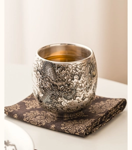 Gros plan détaillé d'une tasse à thé en argent avec motif dragon et textures métalliques