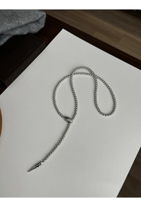 Macro detail of silver snake head pearl necklace with green eye and tassel pendant