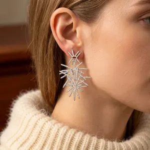 Silver starburst drop earrings with cubic zirconia stones worn by a model in soft lighting