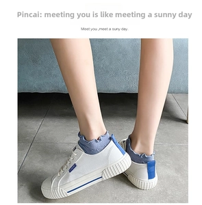 On-foot view of white canvas shoes with blue accents and non-slip rubber soles