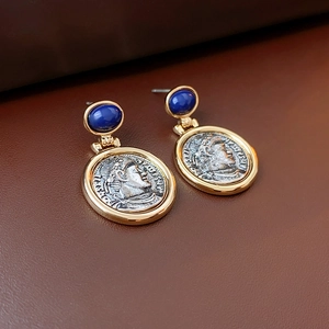 Macro detail of French vintage coin earrings with gold trim and deep blue gemstone
