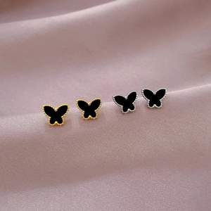 Close-up of butterfly stud earrings with black inlay on premium purple silk fabric