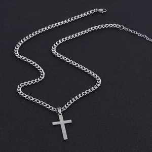 Detailed view of silver cross pendant with double-layer cuban chain on black texture