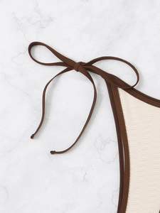 Detail of the bikini side tie with beige wavy texture fabric and brown contrast binding