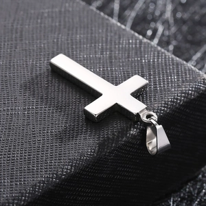 Vue macro d'un pendentif croix en acier poli argenté sur une boîte à bijoux noire