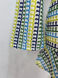 Dettaglio di una manica all'uncinetto colorata con motivo a onde in pizzo giallo verde blu