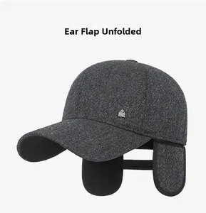 Detailed view of dark grey winter cap with ear flaps extended and metal crown emblem
