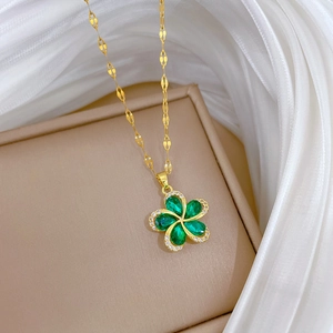 Close-up of golden spinning flower necklace with green oval gemstones and cubic zirconia