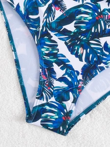 Detail of white swimsuit featuring tropical palm leaf print and durable double-stitched edges