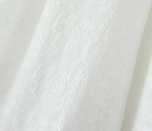 Gros plan sur la broderie florale délicate d'un tissu en dentelle blanche de haute qualité