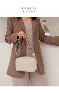 Close-up of beige PU leather crossbody bag with lychee texture and striped strap