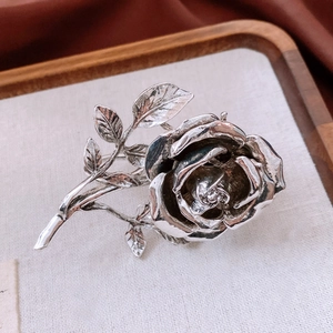 Macro detail of vintage silver rose brooch featuring intricate layered flower petals