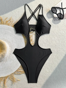 Detail of black cutout one-piece swimsuit with silver heart buckle on woven background