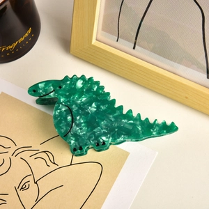Detailed view of green marble acetate dinosaur hair claw clip in a lifestyle setting