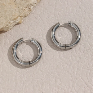 Detailed view of chunky silver hoop earrings on a textured stone surface
