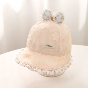 Détail d'un chapeau de soleil pour bébé montrant dentelle blanche et un nœud floral